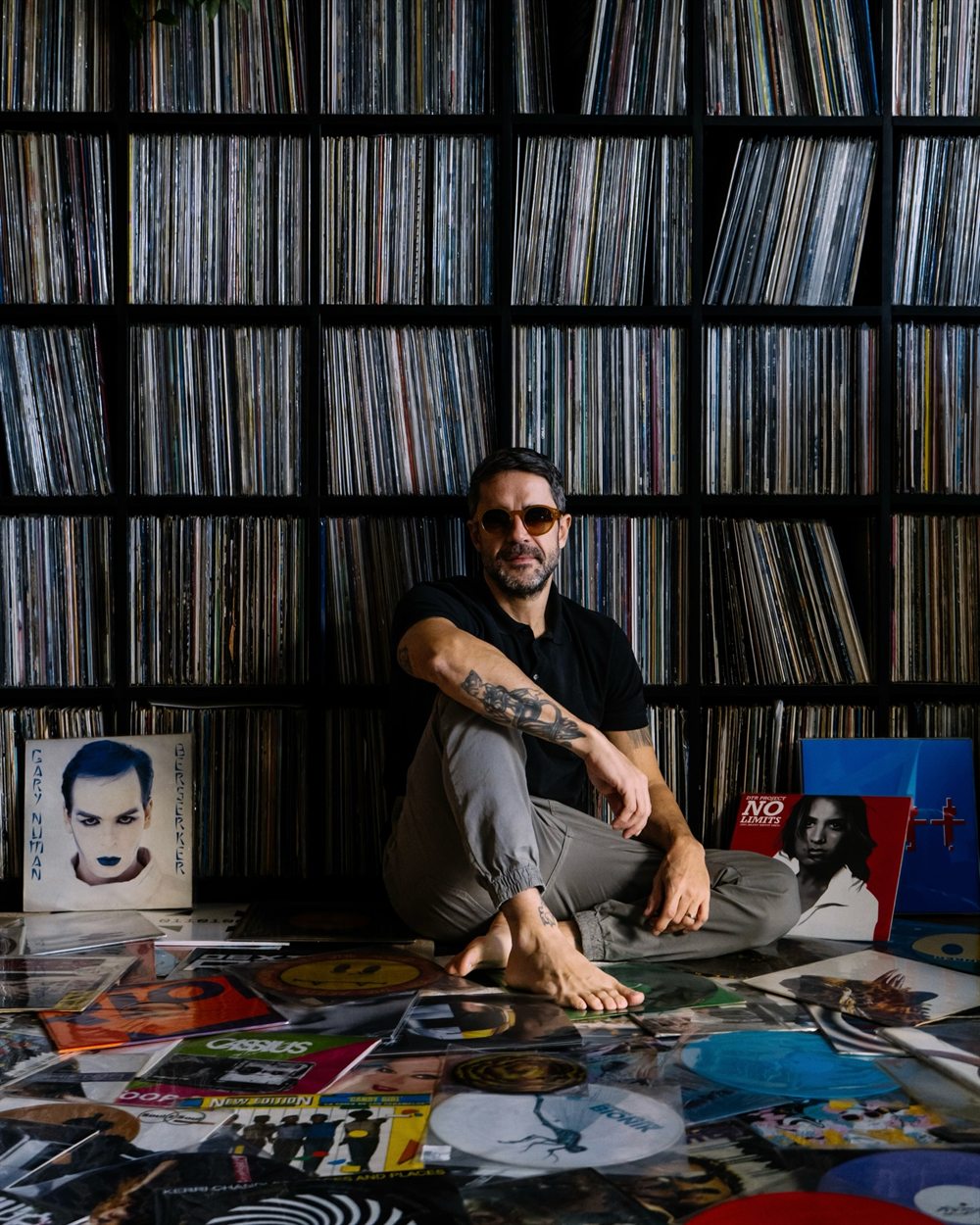 Colecionador diante da parede de discos do Vague.